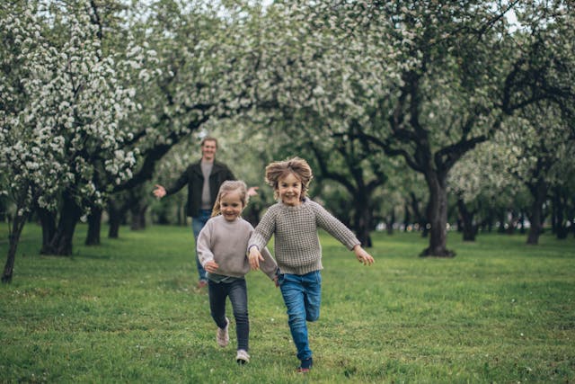 A young family running and playing in a beautiful park in Toronto, representing affordable and easy term life insurance for young families in Toronto.