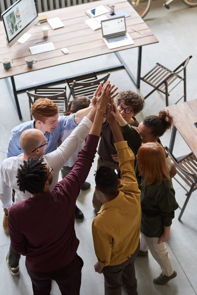 Employees giving each other high fives in celebration, symbolizing teamwork and success in the workplace. They're highlighting the need for "Business Insurance Toronto."