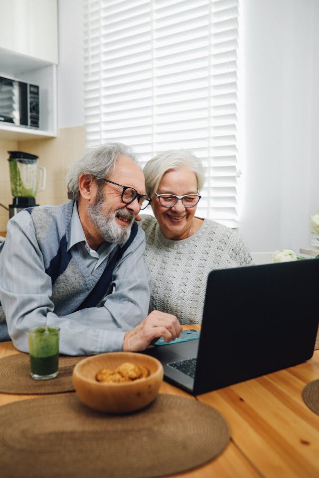 Happy retired couple looking at their portfolio on a laptop, highlighting the benefits of segregated funds, annuities, and retirement planning in Toronto and surrounding areas.