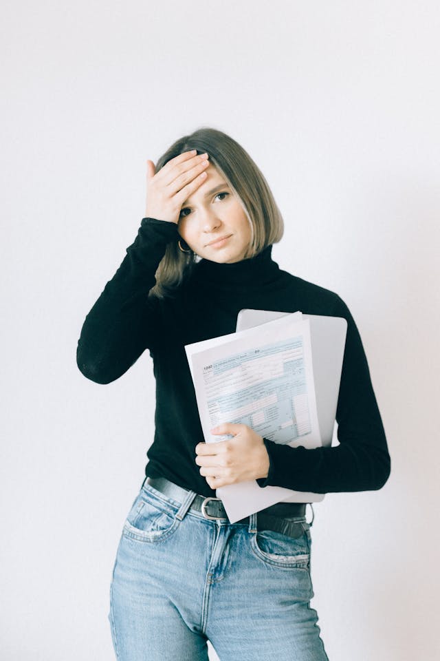  A stressed-out woman surrounded by bills, highlighting the need for business overhead expense insurance. This stresses the importance of "Business Overhead Expense (BOE) Insurance Toronto."